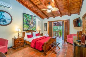 a bedroom with a bed and two chairs and a television at Hotel Villas Lirio in Manuel Antonio