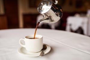 a person pouring coffee into a cup on a table at The Orwell Hotel in Felixstowe