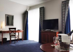 um quarto de hotel com uma televisão e uma mesa com uma cadeira em Hotel Garni Bendiks em Horumersiel