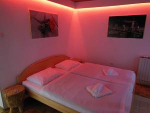 um quarto com uma cama com iluminação rosa em Apartma Jadran em Portorož