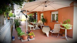 um pátio com um guarda-sol, mesas e cadeiras em Hotel Frida em Rimini