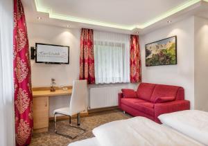 a hotel room with a red chair and a desk at Haus Elisabeth in Mühlbach am Hochkönig