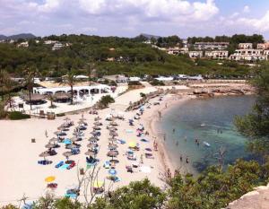 plaża z parasolami i ludzie w wodzie w obiekcie Cala Murada Paradise w mieście Cala Murada