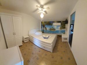 een slaapkamer met een wit bed en een plafondventilator bij Casa Carmen in 2 Mai