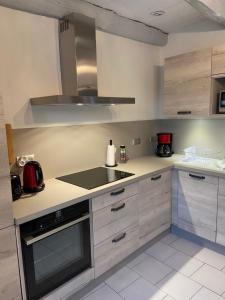 uma cozinha com armários brancos e um forno com placa de fogão em Gîtes de Pouzelande em Notre-Dame-de-Sanilhac