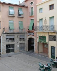 a large pink building with a courtyard with tables and chairs at Casa Estivill in Cornudella