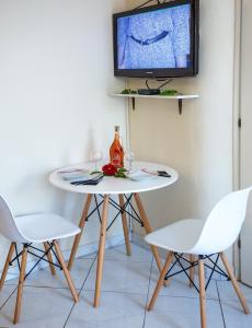 a table with two chairs and a tv on a wall at Ammos Studios & Apartments in Nea Peramos