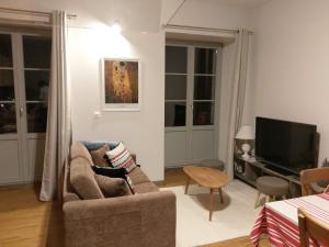 a living room with a couch and a television at Résidence du Parc avec Sauna in Eaux-Bonnes