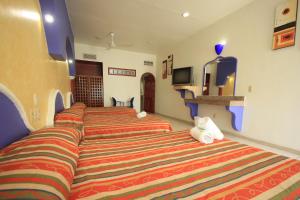 a hotel room with three beds and a tv at Hotel Xestal in Santa Cruz Huatulco