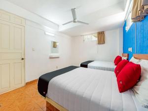 1 dormitorio con 2 camas y almohadas rojas en Capital O Hotel El Mejicano, Acapulco, en Acapulco