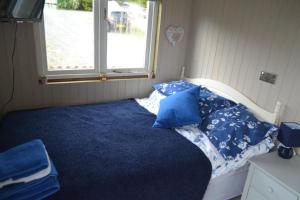 - une chambre avec un lit doté de draps bleus et une fenêtre dans l'établissement Peaceful Shepherd's Hut next to Horse Field, à Morpeth