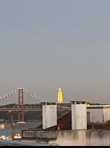 a view of the golden gate bridge and a statue at quarto suite em Belém in Lisbon