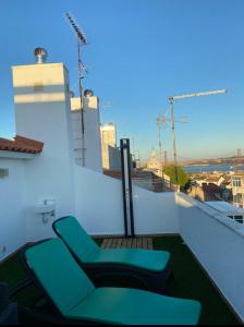 a balcony with two green chairs on a building at quarto suite em Belém in Lisbon