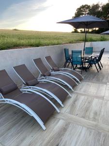 a row of chairs and an umbrella on a patio at Gîtes de Pouzelande in Notre-Dame-de-Sanilhac