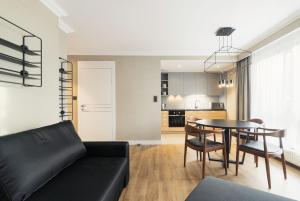 - un salon avec un canapé noir et une table dans l'établissement Grand Apartments - Prestigious Apartment Sopot Victoria Residence, à Sopot