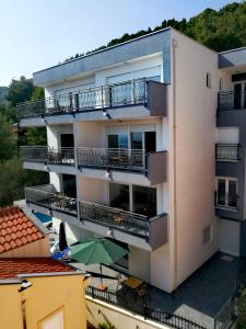 un edificio de apartamentos con balcones, una mesa y una sombrilla en Villa Cologne, en Baška Voda