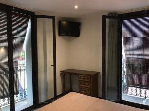 a bedroom with a bed and a table and windows at Hostal Radio Barcelona in Barcelona
