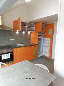 una cucina con armadi arancioni e tavolo da pranzo di la Nichée a Hauteville-Lompnes