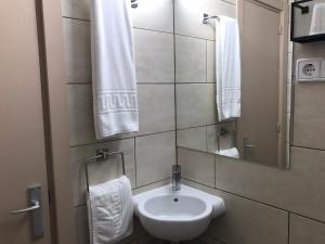 a bathroom with a sink and a mirror and towels at Hostal Radio Barcelona in Barcelona