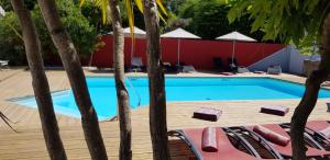 - une piscine bordée de chaises et d'arbres dans l'établissement La Villa en L'île - 2 Piscines & Spa, à Noirmoutier-en-l'lle