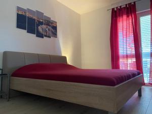 a bed in a bedroom with a red window at Apartmani Ortolio in Viganj