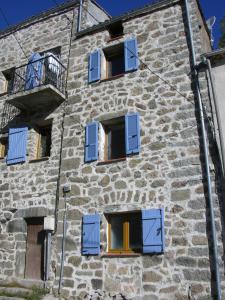 a stone building with blue windows and a balcony at Maison Le Rêve in Evisa