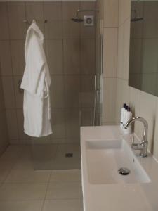 La salle de bains est pourvue d'un lavabo, d'une douche et d'une serviette blanche. dans l'établissement The Suites at Pannells Ash, à Castle Hedingham