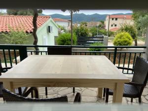 a wooden table on a balcony with two chairs at Apartmani Ortolio in Viganj