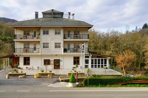 un gran edificio blanco con bancos delante en Hotel A Veiga, en Samos