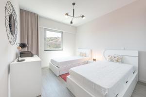 a white bedroom with two beds and a window at Getaway to Blue Paradise at Madeira Island in Funchal