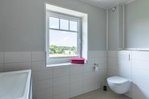 a white bathroom with a window and a toilet at Exclusive Wohnungen auf dem Hudddelhof in Langwedel