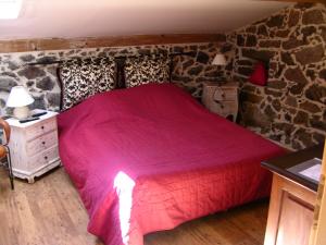 a bedroom with a red bed with a stone wall at Maison Le Rêve in Evisa