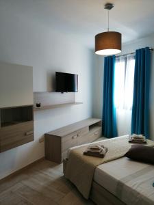 1 dormitorio con 2 camas y TV de pantalla plana en Appartamento Monte Granatico 01, en SantʼAntìoco