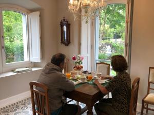 un hombre y una mujer sentados en una mesa en un comedor en Villa Marta Casa de Indianos Passive House, en Villanueva de Ardisana