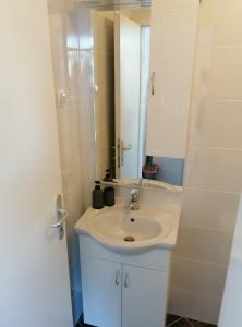 La salle de bains est pourvue d'un lavabo blanc et d'un miroir. dans l'établissement Apartmani Skalinada, à Marina