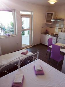 - une cuisine avec une table et des chaises violettes dans la chambre dans l'établissement Apartmani Skalinada, à Marina