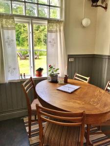 a dining room table with chairs and a large window at Holsby banvaktarstuga in Ransäter