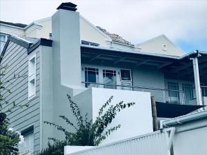 a white house with a fence in front of it at Seaforth Suite in Simonʼs Town
