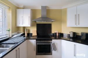 a kitchen with white cabinets and a stove top oven at Swan Place - Comfortable Home in Reading