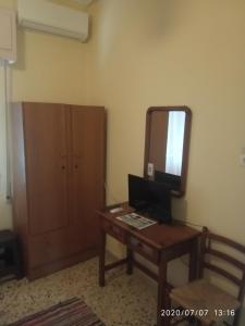 um quarto com uma secretária com um espelho e um computador em Captain's Rooms em Egina