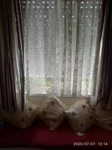 a window with white curtains and pillows on a bed at Captain's Rooms in Aegina Town