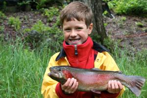 a young boy holding a fish in his hands at Wellsfield Farm Holiday Lodges in Stirling