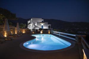 a swimming pool at night with a house in the background at Manthos Place in Mylopotas