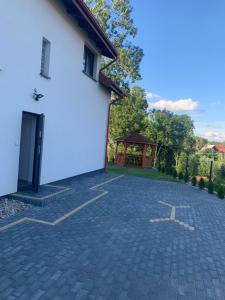 a driveway with a gazebo next to a white building at Apartamenty Wydminy in Wydminy