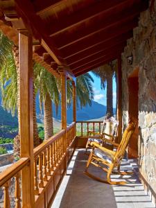 un porche con mecedora y palmeras en Villa Fataga - Unique villa with heated pool, en Fátaga