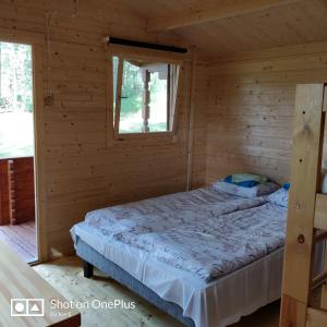 a bed in a log cabin with a window at Rannakodu in Kabli