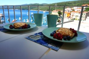 two plates of food on a table on a balcony at Studio Apartment Michelle - Intermezzo with sea view in Rabac