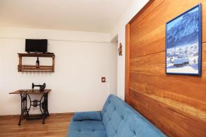 uma sala de estar com um sofá azul e uma parede de madeira em Hospedaria Brigite - Apartamento de Férias em Treze Tílias