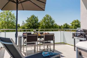 eine Terrasse mit einem Tisch, Stühlen und einem Sonnenschirm in der Unterkunft Luxus SPA Fewo MARITIME DREAM WE 3 in Göhren-Lebbin