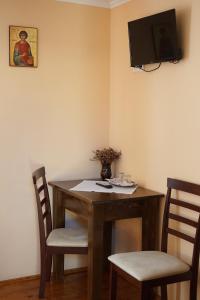 a dining room table with two chairs and a tv on the wall at Casa Ciortea Ana in Sibiel